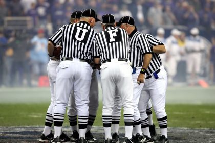 Grupo de oficiais de arbitragem conversa no campo de futebol.