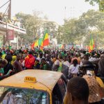 Multidão celebra nas ruas de Dakar, no Senegal, carregando bandeiras do país.