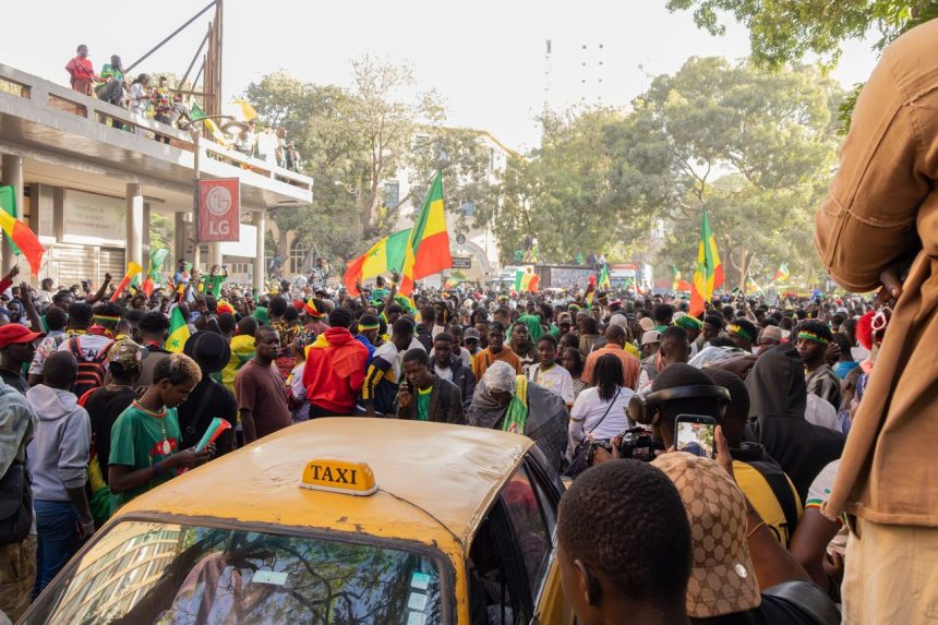Multidão celebra nas ruas de Dakar, no Senegal, carregando bandeiras do país.