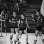 Equipe feminina de voleibol comemora após uma jogada bem-sucedida em quadra.