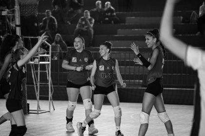 Equipe feminina de voleibol comemora após uma jogada bem-sucedida em quadra.