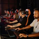 Jogadores concentrados disputam uma competição de futebol eletrônico em uma arena de esports.