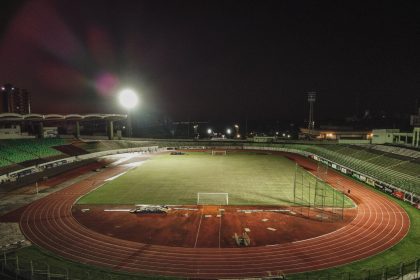 Vista aérea noturna do Estádio Willie Davids, com o campo de futebol iluminado e a pista ao redor.